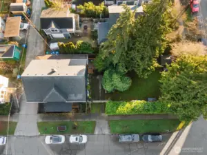 This aerial view shows the positioning of the house all the way on the left side of the corner lot, with plenty of open green yard to the right.
