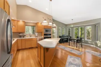 The chef's kitchen features a large center island, gas cooktop, & stainless appliances.