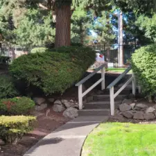 Stairs heading toward front of complex by pool area. Attractive iron fencing. Wooded area across the street from complex adding to a more serene and peaceful setting.