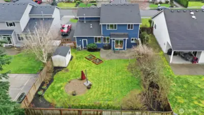 Aerial view of your new backyard oasis! Fully fenced, wonderful paved patio, garden beds, trellis, fire pit space, and a storage shed!