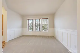 Natural light fills this space through large windows with wooden blinds. The wainscoting adds a touch of style and luxury to this fabulous room.