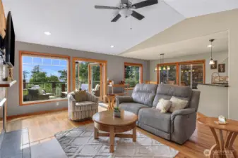 Enjoy indoor-outdoor living from the heart of the home—French doors open to a spacious deck framed by trees and filtered views of the water. Thoughtfully arranged furniture encourages gathering in this sunlit retreat.