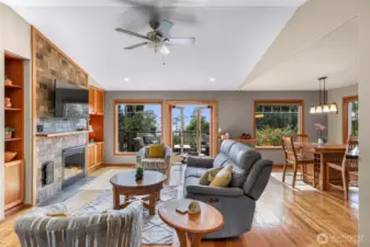 The open-concept living area invites relaxation with its vaulted ceilings, custom stone fireplace, and panoramic views of Birch Bay through oversized windows and French doors. Natural light floods the space, enhancing the warm wood accents and seamless flow to the expansive deck.