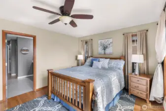 The primary bedroom is generously sized with ample wall space, hardwood floors, and ceiling fan comfort—anchoring the home with quiet sophistication and a connection to the backyard.