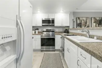Updated kitchen with granite counters, white cabinetry, and stainless steel appliances — all in the heart of the desirable Klahanie community.