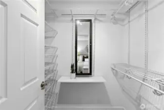 Spacious walk-in closet featuring built-in shelving for organized storage, a mirror, and a custom jewelry cabinet - combining style and functionality in one luxurious space.