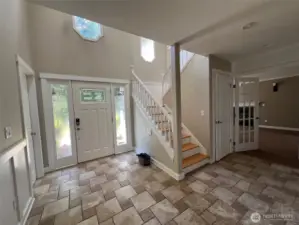 Bright foyer featuring decorative glass door, natural light, and open staircase