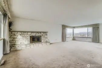Over sized living room with fireplace and view of the mountains and valley.  Hardwoods under carpet.