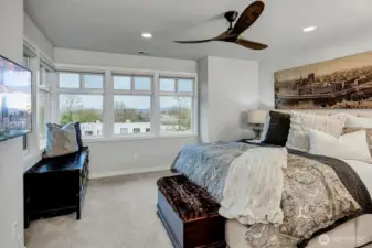 Primary bedroom with wall of windows and Restoration Hardware fan.