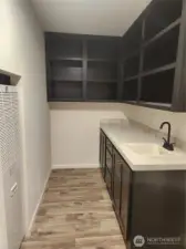 This utility room has matching cabinetry as the kitchen with lots of storage room, as well as a utility sink.  Furnace to the left of the photo.