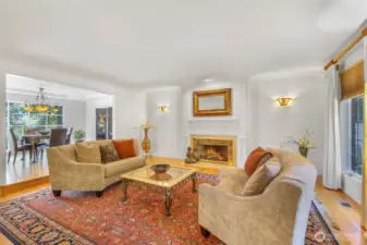 The formal living room offers a welcoming retreat with its traditional fireplace and elegant millwork. Generously sized windows bring in natural light, enhancing the warm hardwood floors and creating a bright, comfortable space for gatherings.