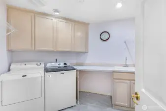 The laundry room is designed with efficiency in mind, offering plenty of cabinetry, counter space, and a utility sink. Thoughtful organization makes everyday tasks more manageable.