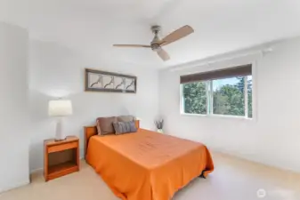 Another secondary bedroom provides flexibility for family, guests, or additional workspace, with expansive windows framing treetop views.