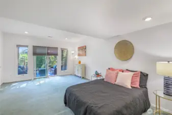 A spacious lower-level bedroom features bright windows and patio access, creating a comfortable private retreat for guests or multi-generational living.
