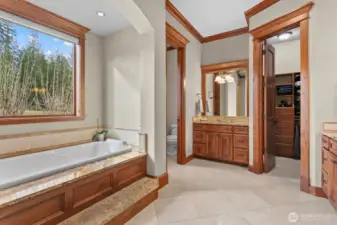 Primary Bathroom with jetted tub, his and hers walk in closets with wood built in shelving, and shower.
