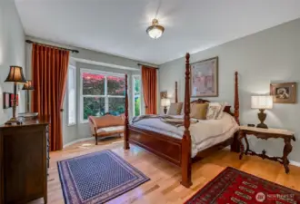 The spacious primary suite has hardwood floors, two walk-in closets and overlooks the backyard gardens.