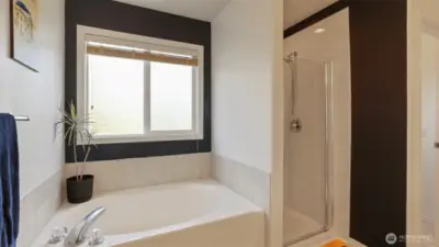 Designed with contemporary style in mind, this luxurious bathroom showcases a sleek aesthetic, a large corner soaking tub, and a separate glass-enclosed shower