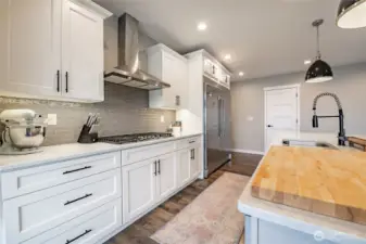 Gas cooktop with hood, tile backsplash, abundant counter and cabinet space, under-cabinet lighting and more