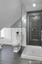 Spacious walk-in shower with seamless glass, tile floors, and classic wainscoting come together to create a beautifully finished space.