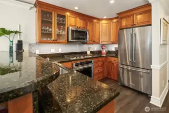 Chef’s kitchen with granite counters, stainless steel appliances, under cabinet lighting, and gas cooking.