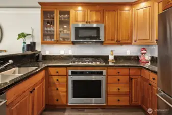 Chef’s kitchen with granite counters, stainless steel appliances, under cabinet lighting, and gas cooking.