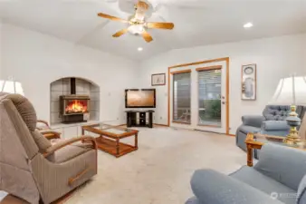 Gas stove and ceiling fan in vaulted family room and door to covered patio and backyard