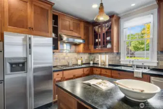 Exquisite custom cabinetry, handcrafted from rich mahogany by a renowned local artisan, showcases intricate craftsmanship and restoration glass panes that reflect the home's signature arched doors.