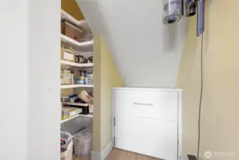 As we head out of the Family room, back toward the office, we continue on to find the Pantry. Tap lights adorn each shelf helping you find just the right snack. Notice the handled drawer just in front of you? That is a heavy-duty pull-outy drawer for your lager appliance or stock pots. Just below the drawer is the crawl space access panel.
