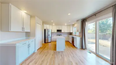 Updated kitchen featuring white shaker-style cabinetry, sleek stainless steel appliances, and a large center island with quartz countertops and ample drawer storage.