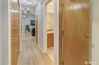 Hallway showing bathroom and bedroom doors, hallway closet contains the laundry