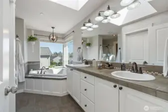 Gorgeous primary bath with double sinks, soaking tub, separate shower, toilet room and a large walk-in closet all lit up beautifully with a brightly lit skylight!