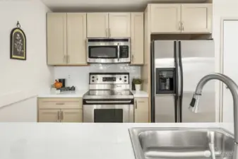 A stylish kitchen featuring brand-new stainless steel appliances, luxury LVP flooring, and an updated light fixture.