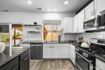 Refreshed kitchen featuring newer appliances, updated flooring, stylish tile backsplash, modern counters, fresh paint, and contemporary fixtures.