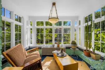 A peaceful sunroom surrounded by windows on all sides, perfect for relaxing and enjoying natural light with a good book.