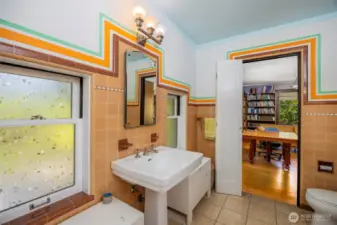 This bathroom features vibrant tilework and natural light from two windows, with a door that connects directly to the office.