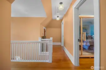 The third-floor landing opens to two wood-floored rooms.