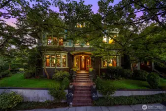 The home shines warmly at night, beautifully illuminated to showcase its classic Tudor charm.