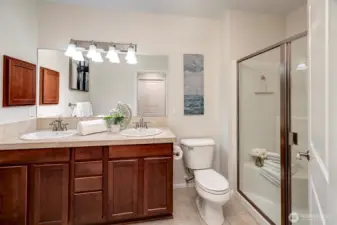 Primary ensuite with double vanity sinks, medicine cabinet, and a walk-iin shower with bench seat.