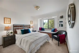 Bedroom Two, located on the main level,  features new wall-to-wall carpet, a built-in  bench seat with storaage below the window,  and two closet doors with mirrored doors.