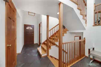 Timeless staircases with wood balustrades  keeps the elegant foyer feeling open and  welcoming! Durable slate flooring here keep  this area easy to care for!