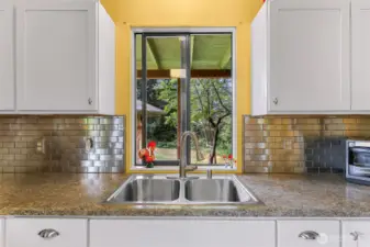 Slight retro feel with the backsplash here and the kitchen cabinetry knobs.  Nice view from the double sink into the backyard.