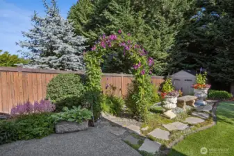 A magical backyard with a vibrant flower garden and a charming storage shed creates a serene and enchanting outdoor retreat.