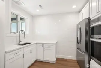 Butlers pantry with tiled walls and lots of light includes 2nd refrigerator, double in-wall oven, sink, storage, washer and dryer.