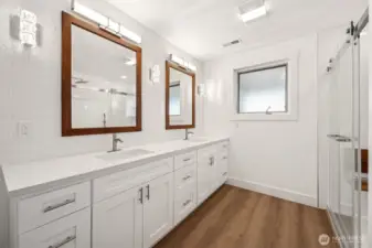A primary bathroom with large double vanity, custom tile shower and lots of light.
