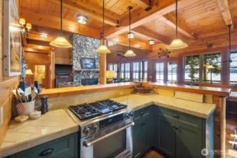 THE KITCHEN OVERLOOKING THE GREAT ROOM - RIVER ROCK FIREPLACE AND WATER VIEWS