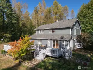 Welcome home. Dappled sunlight filters through the trees and across the wraparound deck—the perfect place to unwind as summer evenings stretch long into golden hour.