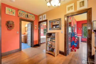 Upper-floor hallway landing with hardwood floors and doors leading to oversized bedrooms, showcasing the home's spacious layout.