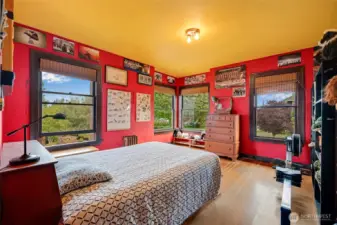 Second oversized upstairs bedroom with abundant natural light, large windows with views, and classic hardwood floors.