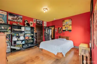 Second oversized upstairs bedroom with original hardwood floors, radiator, large windows, and abundant natural light.