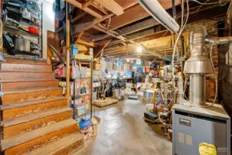 Spacious basement with wood stairs, ample storage shelving, and mechanical systems — ready for expansion opportunities.